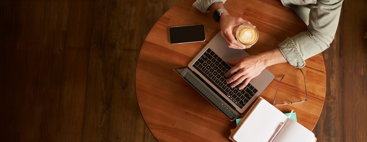 Person working on a laptop at a wooden table